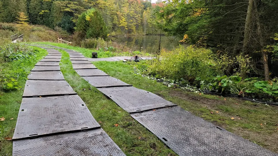 Two temporary Trak Mat access tracks crossing uneven lakeside terrain